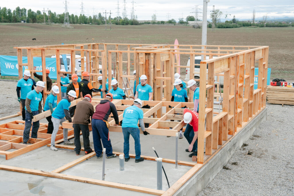 General construction team of volunteers lifting wood slab